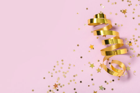 Beautiful golden confetti in shape of star and serpentine on lilac backgroundの写真素材