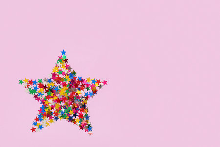 Star made of beautiful colorful confetti on lilac backgroundの写真素材