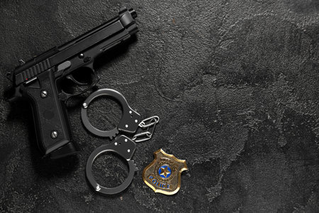 Handcuffs, gun and police shield on dark backgroundの写真素材