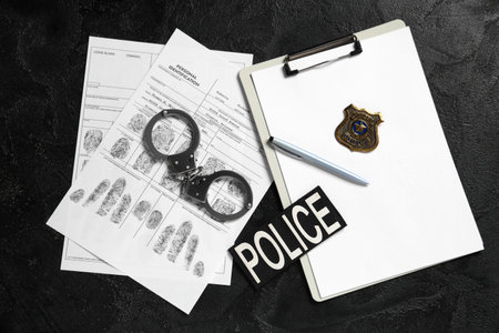 Handcuffs, clipboard, fingerprints sheets and police shield on dark backgroundの写真素材