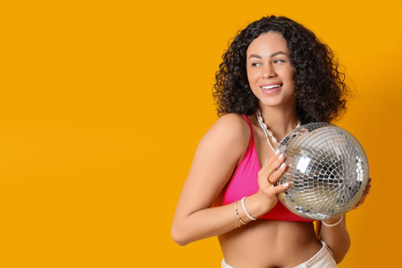 Beautiful woman with disco ball on yellow backgroundの写真素材