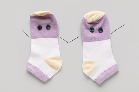 Funny socks with eyes made of buttons on gray background. Friendship Day celebrationの写真素材