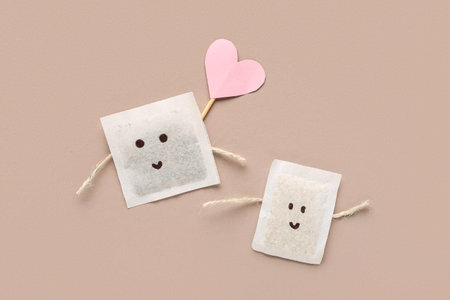 Funny tea bags with drawn faces and paper heart on color background. Friendship Day celebrationの写真素材