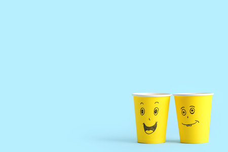 Funny paper cups with drawn faces on color background. Friendship Day celebrationの写真素材