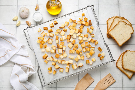 Baking rack with crunchy croutons and garlic on white tile backgroundの写真素材