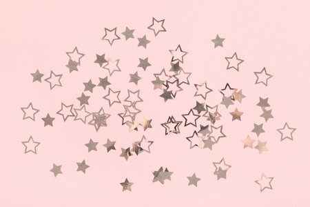 Beautiful silver confetti in the shape of star on pink backgroundの写真素材