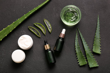 Different cosmetic products with aloe vera leaves on black backgroundの写真素材
