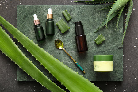 Different cosmetic products with aloe vera leaves on black backgroundの写真素材