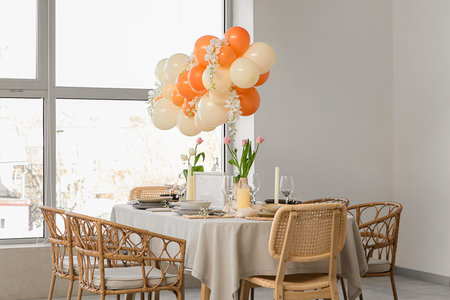 Elegant table setting with blank frame, beautiful flowers and balloons in light dining room