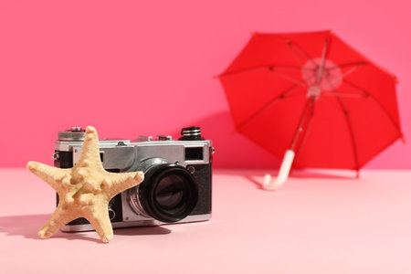 Vintage photo camera, starfish and mini umbrella on color backgroundの写真素材