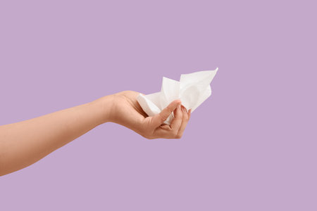 Female hand with crumpled paper napkin on lilac background