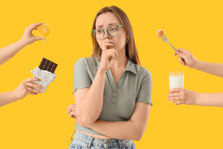 Thoughtful young woman and hands with products on yellow background. Food Allergy Awareness Month