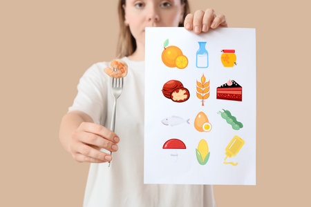 Young woman with list of products and shrimp on beige background, closeup. Food Allergy Awareness Monthの写真素材