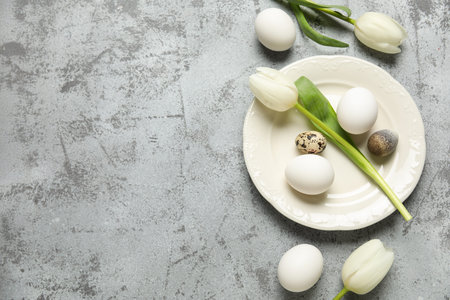 Festive table setting with Easter eggs and tulip flowers on gray grunge background