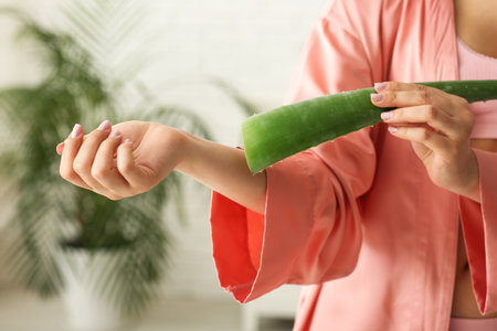 Pretty young woman using aloe vera leaf in bathroom, closeupの写真素材