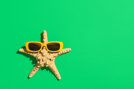 Starfish with stylish sunglasses on green backgroundの写真素材
