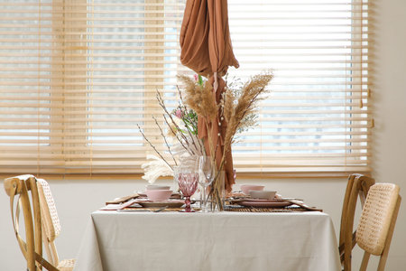 Elegant table setting with beautiful flowers, pampas grass and willow branches in stylish dining...