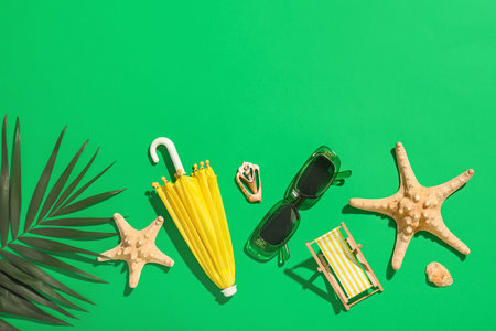 Composition with stylish sunglasses, mini beach accessories and starfishes on green backgroundの写真素材