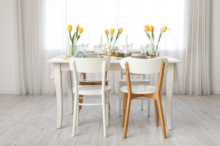 Elegant table setting with beautiful tulip flowers and candles in light dining room