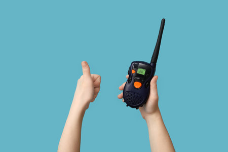 Female hands with radio transmitter showing thumb-up on blue backgroundの写真素材