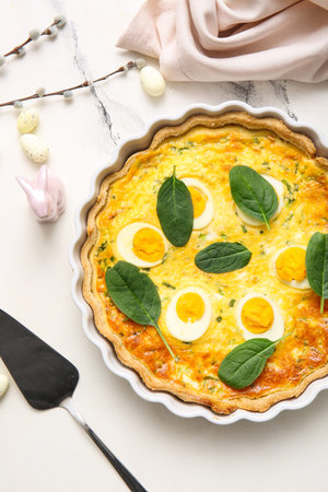 Delicious Easter egg tart with spinach leaves and pussy willow branches on white background