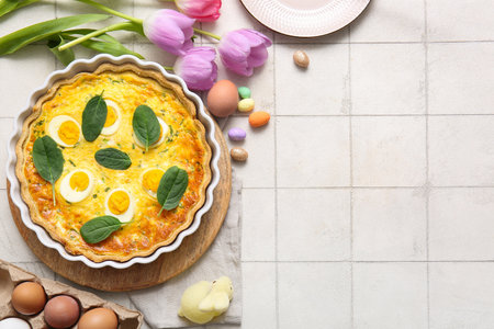 Delicious Easter egg tart with spinach leaves on white tile backgroundの写真素材