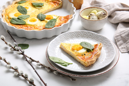 Cut Easter egg tart with spinach leaves and pussy willow branches on white background, closeupの写真素材