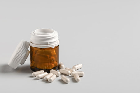 Jar with white hard capsules on gray backgroundの写真素材