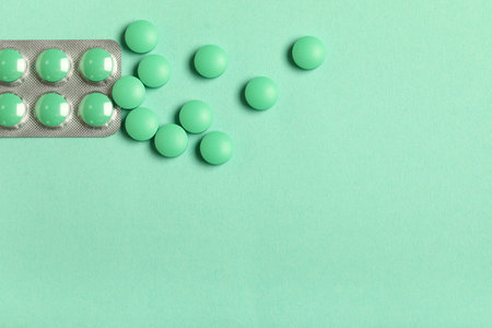 Green pills in blister pack on color backgroundの写真素材