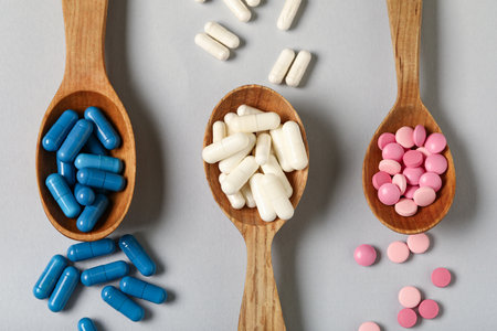 Wooden spoons with different pills on gray backgroundの写真素材