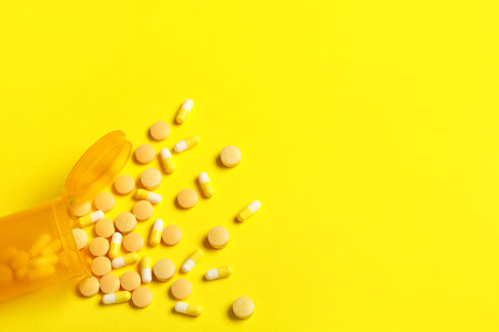 Jar with different pills on yellow backgroundの写真素材