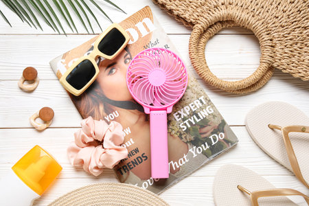 Bag with female summer accessories, fashion magazine and mini fan on white wooden backgroundの写真素材