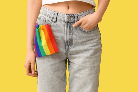 Woman with LGBT flag in her pocket of jeans on yellow background, closeupの写真素材
