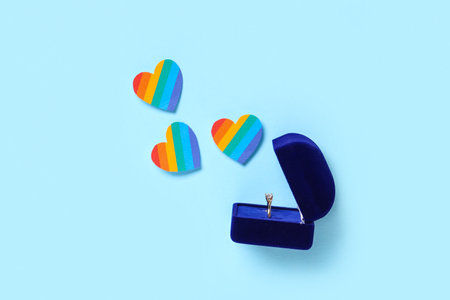 Engagement ring with rainbow hearts on blue background. LGBT conceptの写真素材