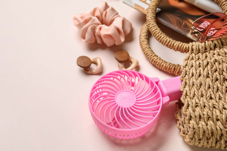 Bag with female summer accessories and mini fan on light pink backgroundの写真素材