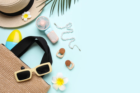 Bag with female summer accessories and mini fan on blue backgroundの写真素材