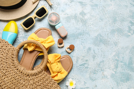 Bag with female summer accessories and mini fan on blue grunge background with space for textの写真素材