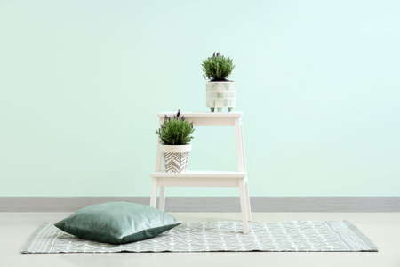 Lavender flowers on stool and pillow near mint wall in room