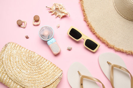 Bag with female summer accessories and mini fan on pink backgroundの写真素材