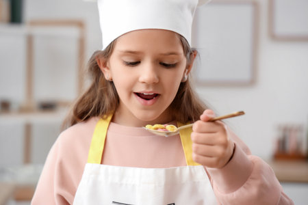 Cute chef eating cereal rings in kitchen, closeupの写真素材