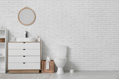 Interior of restroom with toilet bowl, sink and mirror