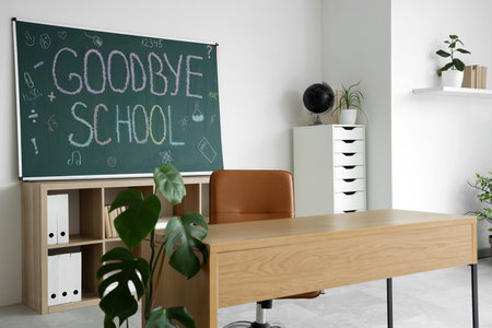 Blackboard with text GOODBYE SCHOOL on light wall in classroom interiorの写真素材