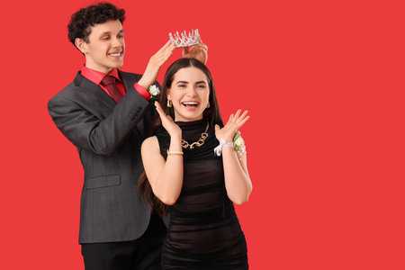 Young boy crowning his prom date on red backgroundの写真素材