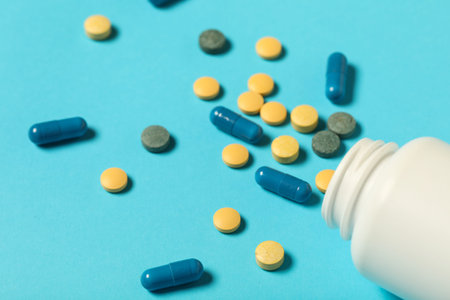 Jar with different pills on blue background, closeup