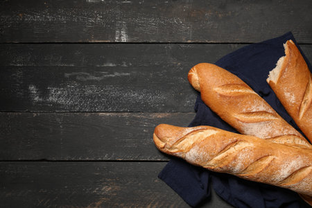 Fresh baguettes on black wooden background