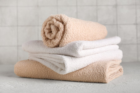 Set of clean towels on table against light tile wallの写真素材
