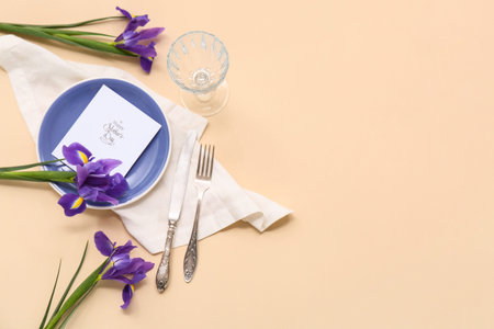 Beautiful table setting with greeting card and iris flowers on beige background. Mother's Day...