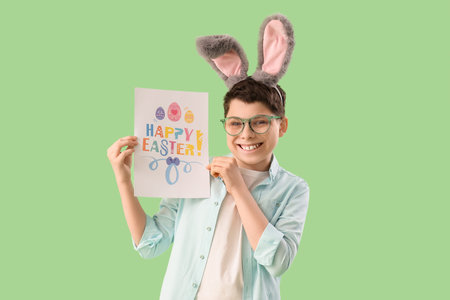 Teenage boy in bunny ears holding paper with text HAPPY EASTER on green background