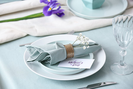 Beautiful table setting for Mother's Day celebration with greeting card and gypsophila flowers,...