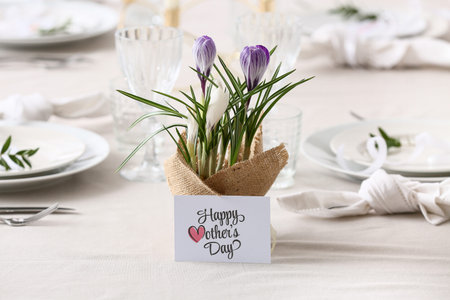 Table setting for Mother's Day celebration with beautiful flowers and greeting card, closeup